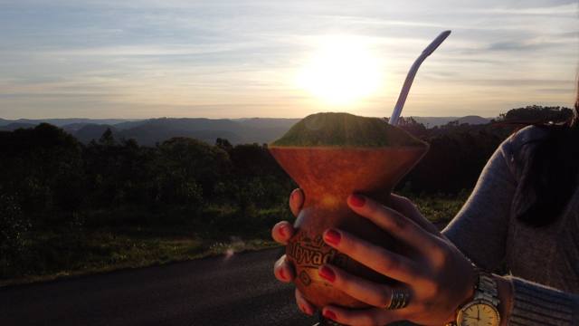 Manos alzando el mate Cultyvada contra el atardecer